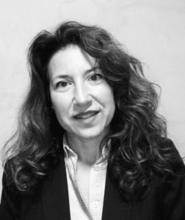 Mujer con cabello rizado y expresión profesional en imagen en blanco y negro.